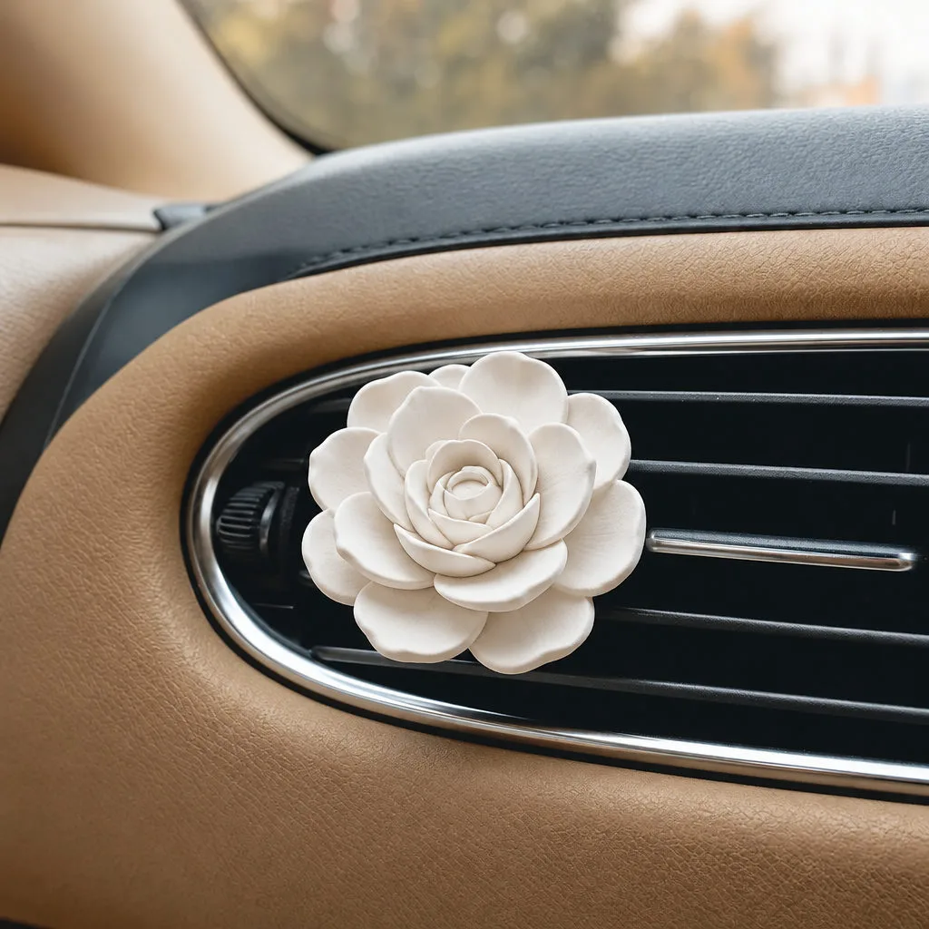 White plaster flower diffuser placed in a car vent beside an amber fragrance bottle